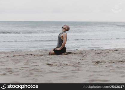 side view man beach meditating