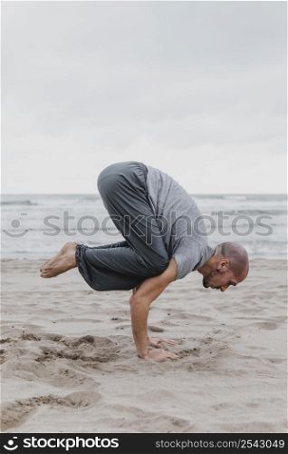 side view man beach practicing yoga