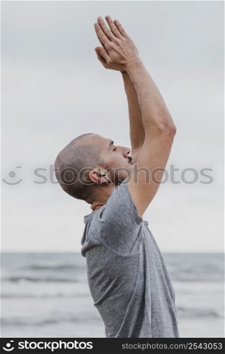 side view man doing yoga raising his arms up outdoors