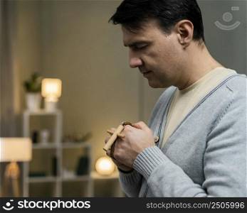 side view man holding wooden cross praying