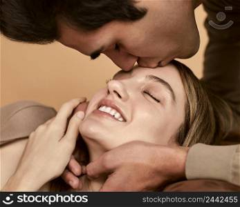side view man kissing smiley woman forehead