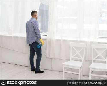 side view man looking through window while cleaning