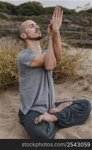 side view man outside meditating while doing yoga 2