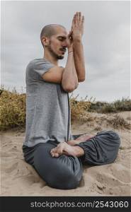 side view man outside meditating while doing yoga
