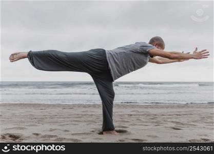 side view man practicing yoga beach