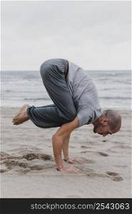 side view man practicing yoga positions beach