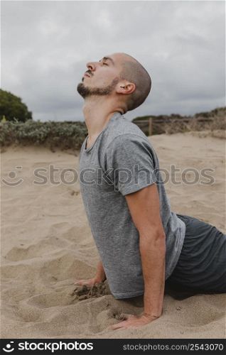 side view man sand doing yoga