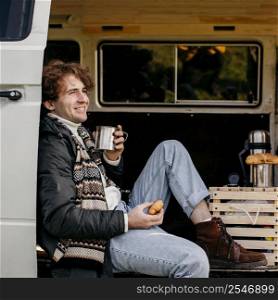 side view man sitting van drinking his coffee