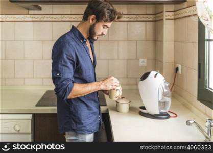 side view man standing kitchen holding coffee mug