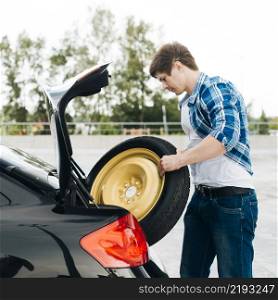 side view man taking out spare tire