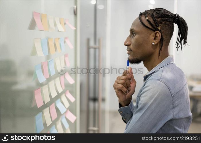 side view man thinking office while looking sticky notes