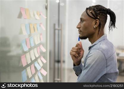 side view man thinking office while looking sticky notes