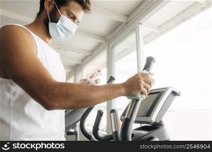 side view man with medical mask using gym equipment