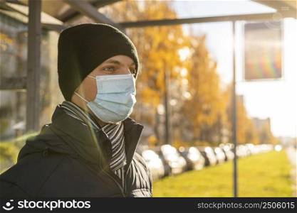 side view man with medical mask waiting bus