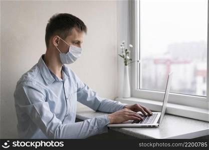 side view man with medical mask working smartphone