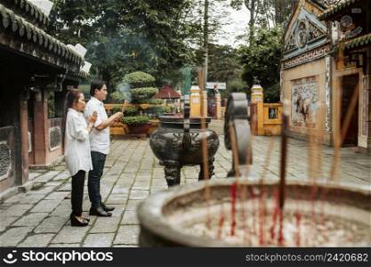 side view man woman praying temple with burning incense