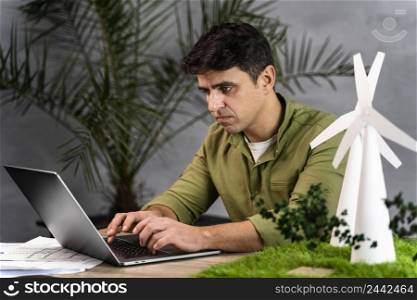 side view man working eco friendly wind power project with laptop