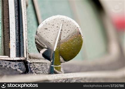 side view mirror of a classic car in the rain