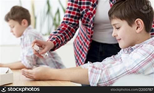 side view mother spraying sanitizer child s hands