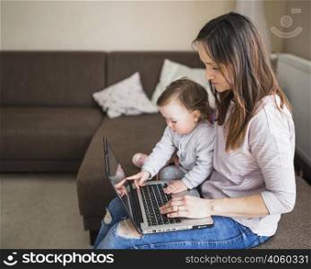 side view mother with her child sitting sofa using laptop