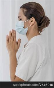 side view nurse with medical mask praying