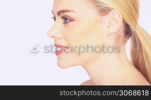 Side view of a beautiful blond woman with her long hair in a ponytail and a gentle smile, isolated on white