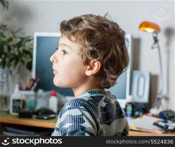 Side view of a little boy at table in the room