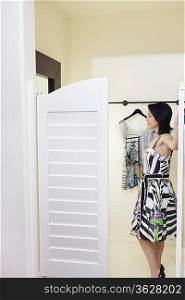 Side view of a mid adult woman standing at doorway of dressing room in fashion boutique