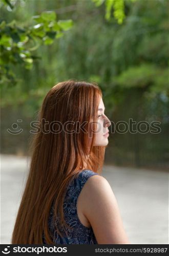Side view of a red haired women outdoors with blank expression on her pretty face