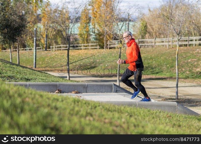 Side view of a senior caucasian athlete man training running up and down the stairs outdoors in a park in a sunny day
