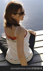 Side view of a woman sitting on a dock