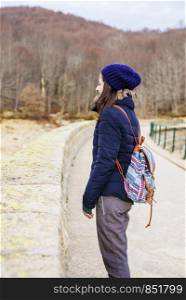 Side view of a young backpacker woman standing while looking away in the forest