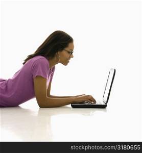 Side view of African American mid adult woman lying on floor using laptop.