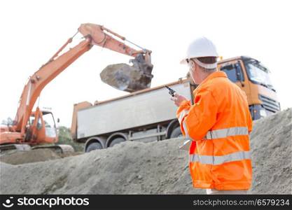 Side view of architect using walkie-talkie while working at construction site