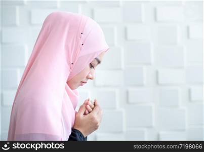 side view of asian beautiful young muslim student woman prayer in hijab praying on carpet mat indoors