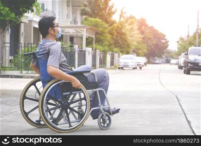 Side view of Asian disabled man wears protective mask on wheelchair crossing the street in housing estate