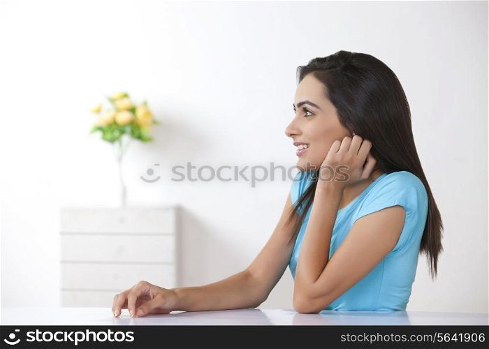 Side view of beautiful young woman looking away at home