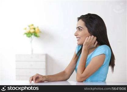 Side view of beautiful young woman looking away at home