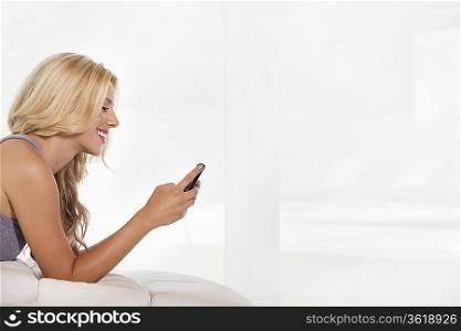 Side view of beautiful young woman reading text message on cell phone