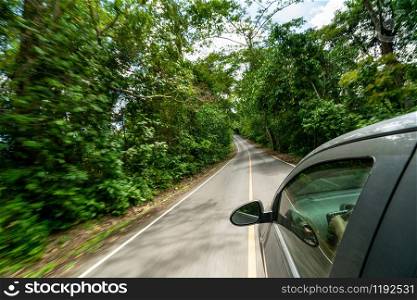 Side view of black car driving on road in forest highway in summer. Travel and explore concept.