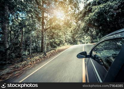 Side view of black car driving on road in forest highway in summer. Travel and explore concept.