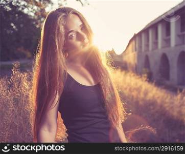 Side view of blonde 20s female girl at sunset, backlit. Deep mysterious look. Pretty young lady outdoors rejoice of warm weather fall