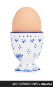 side view of brown boiled egg in ceramic egg cup with a pointy end up isolated on white background
