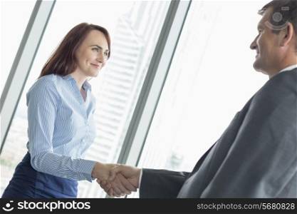 Side view of business people shaking hands in office