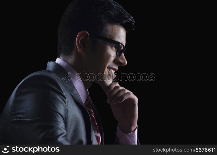 Side view of businessman with hand on chin against black background