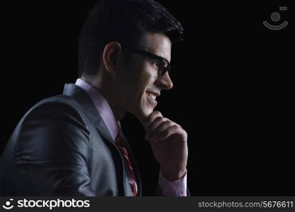 Side view of businessman with hand on chin against black background