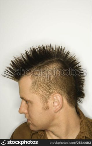 Side view of Caucasian man with mohawk against white background.