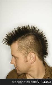 Side view of Caucasian man with mohawk against white background.
