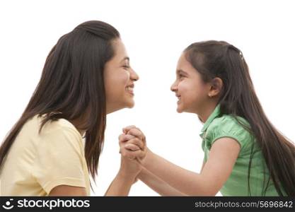 Side view of cheerful mother and daughter holding hands over white background