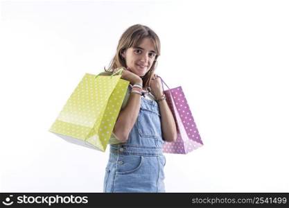 Side view of cheerful young woman girl in jumpsuit hold package bag with purchases isolated on white background studio portrait. Shopping discount sale concept. Mock up copy space. Looking camera.